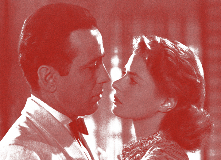 A man and woman face each other closely, about to kiss, in vintage attire indoors with a red overlay.